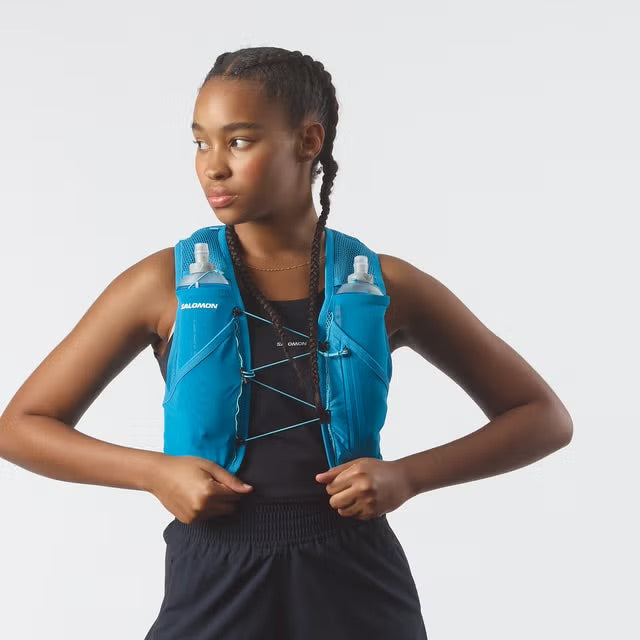 Person wearing a blue running vest with water bottles on a white background